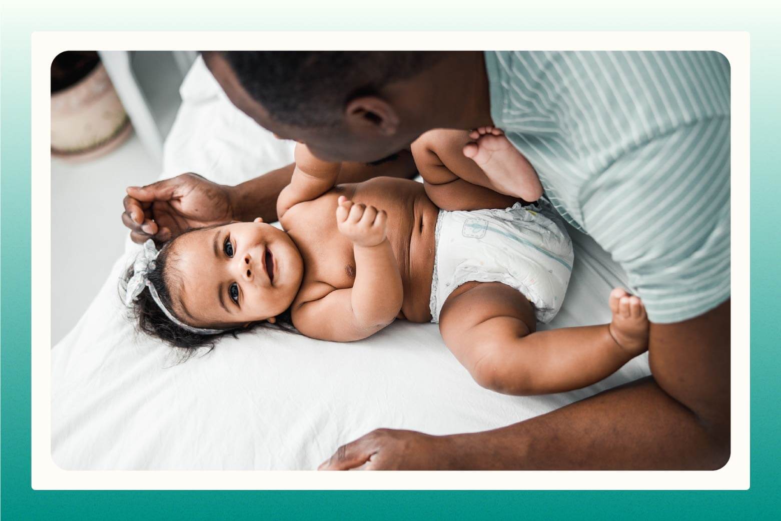 Close up of man leaning over smiling baby girl dressed in her diaper