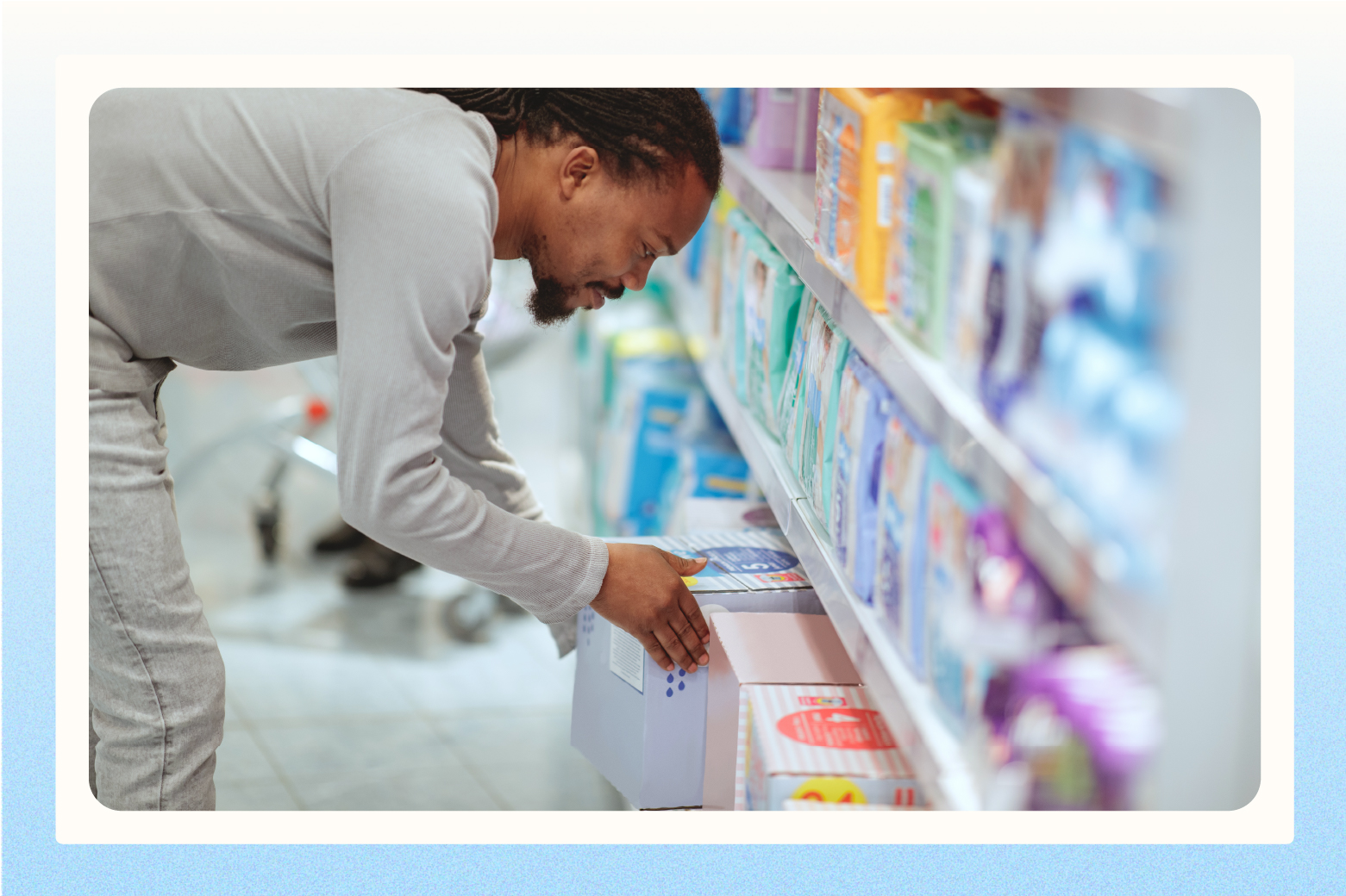 Man leaning over to pull box of diapers from grocery store bottom shelf