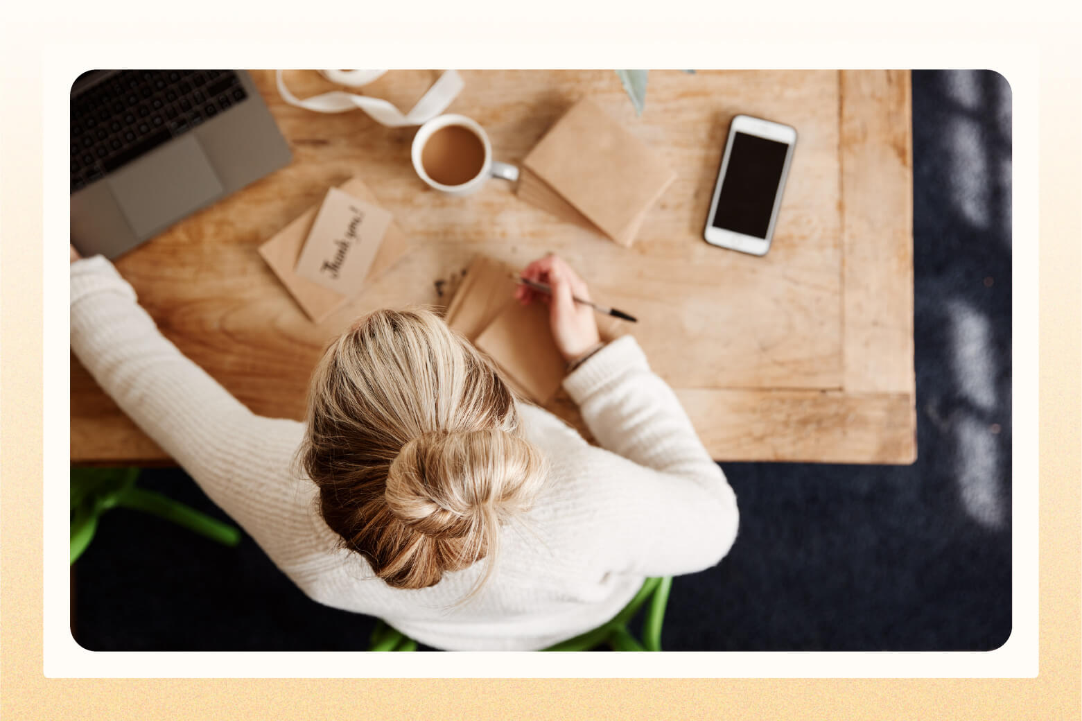 Overhead view of woman at desk writing out thank you cards